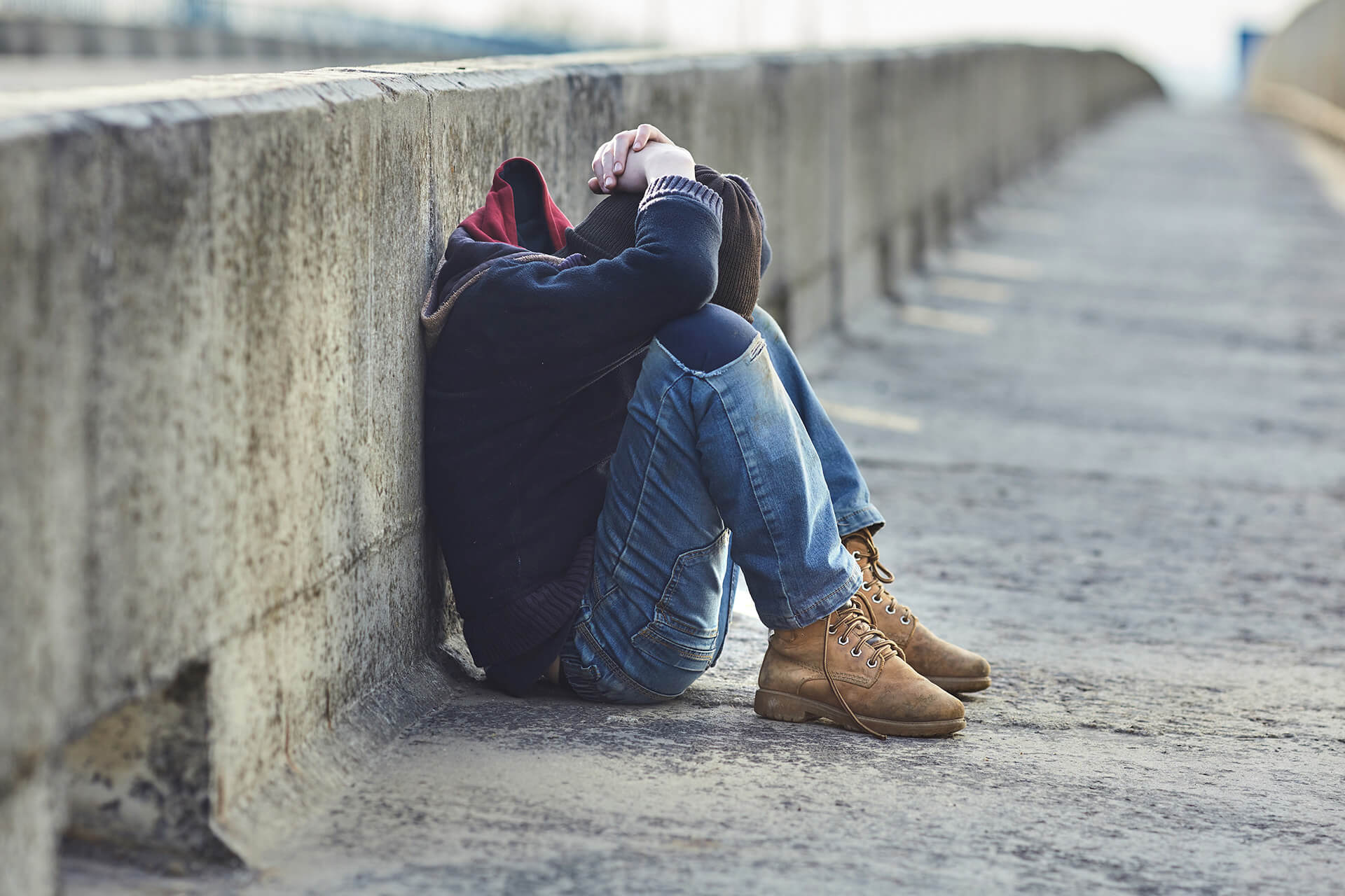 teenager sitting on ground with head in hands