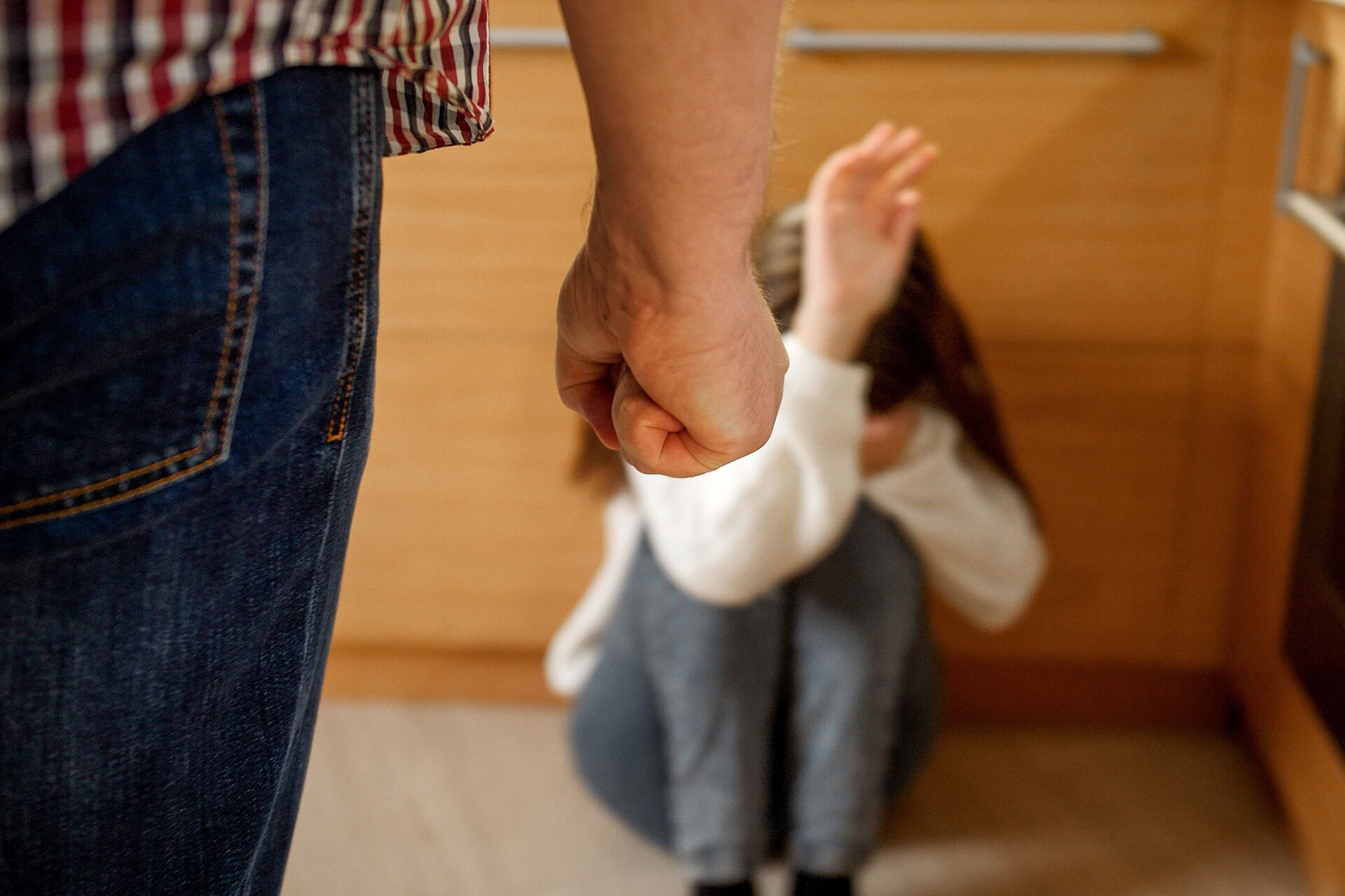 girl cowering on floor from man with closed first